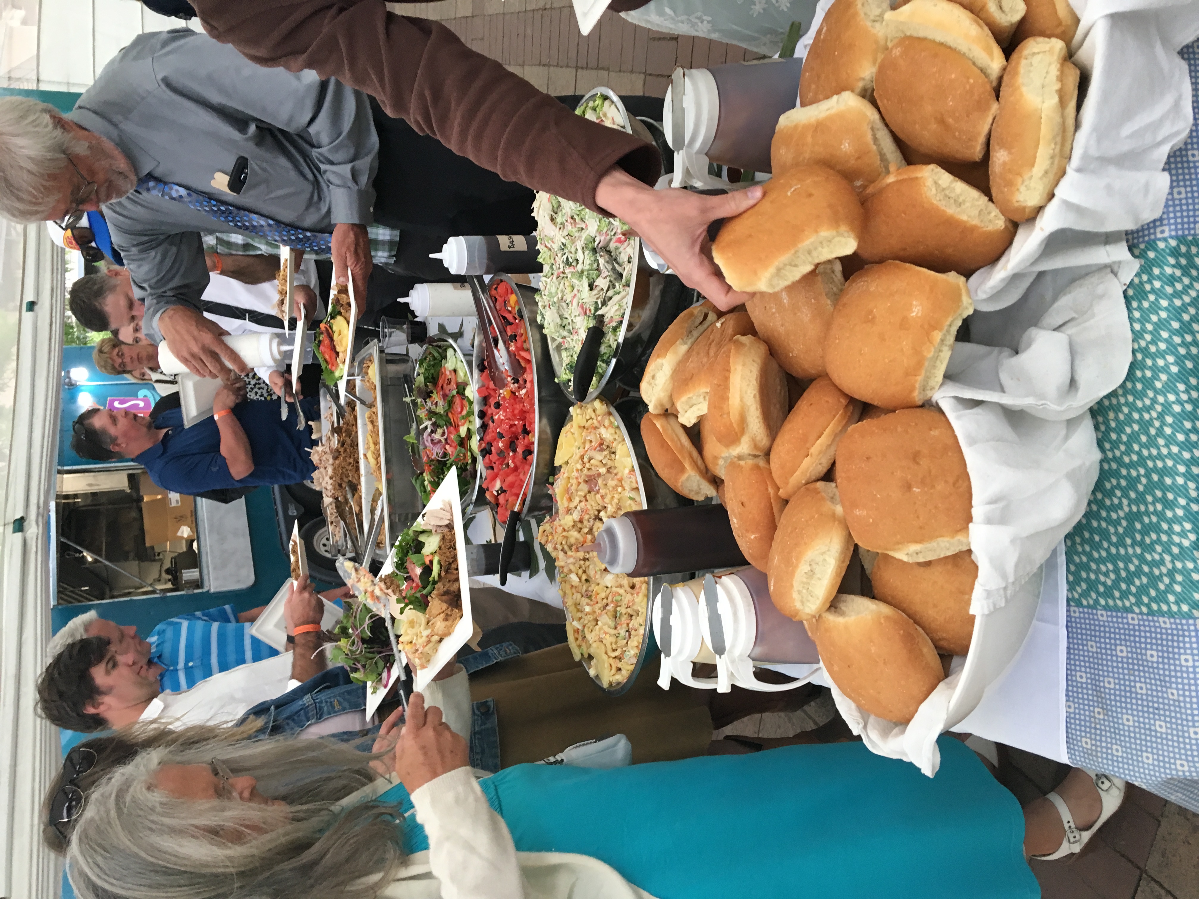 a group of people standing around a table full of food