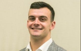 a man wearing a suit and tie smiling at the camera