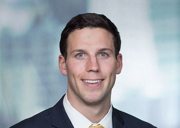 a man wearing a suit and tie smiling at the camera