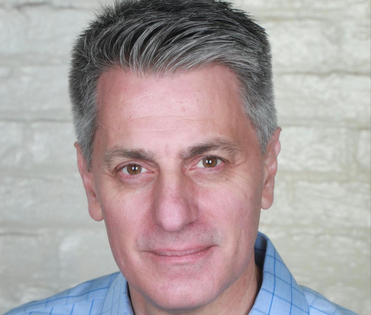 a man wearing a blue shirt and smiling at the camera