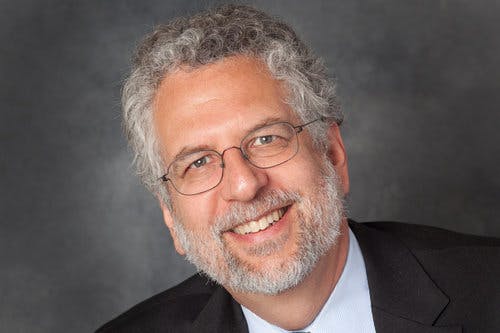 a man wearing glasses and smiling at the camera