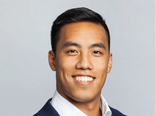 a man wearing a suit and tie smiling at the camera