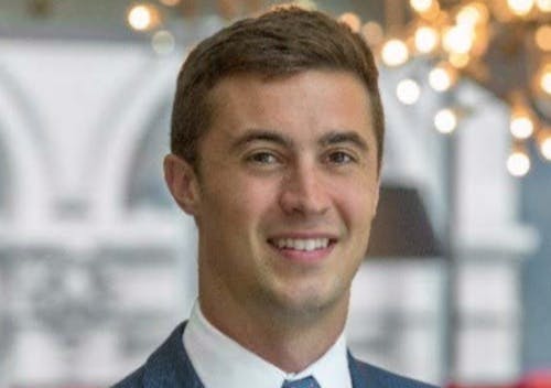a man wearing a suit and tie smiling at the camera
