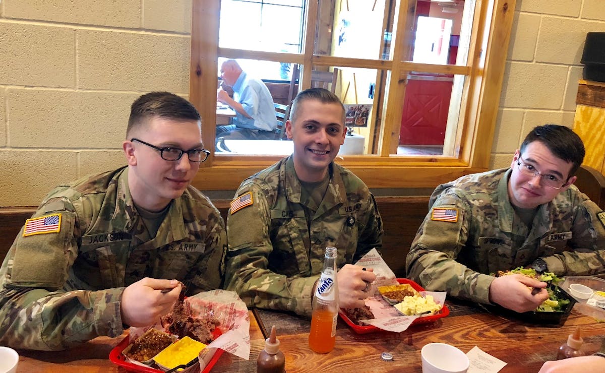 a group of people in uniform sitting at a table eating food