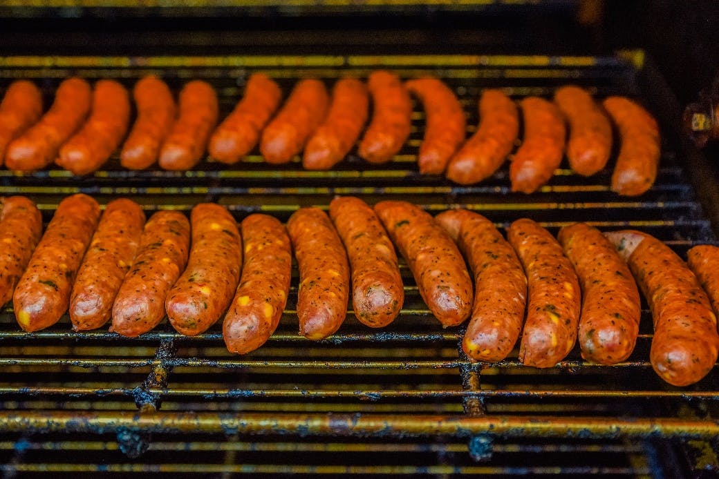 a bunch of hot dogs cooking on a grill
