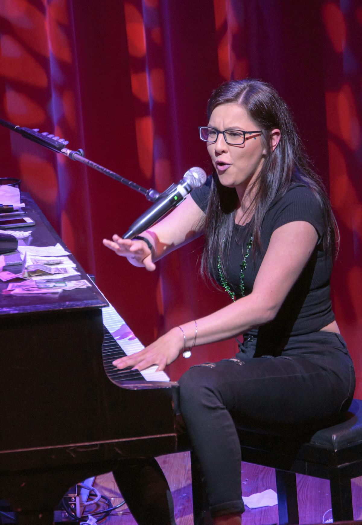 a woman sitting on a stage in front of a piano