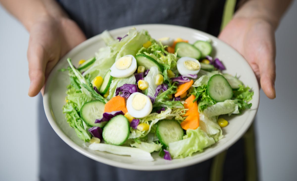 a person holding a bowl of salad
