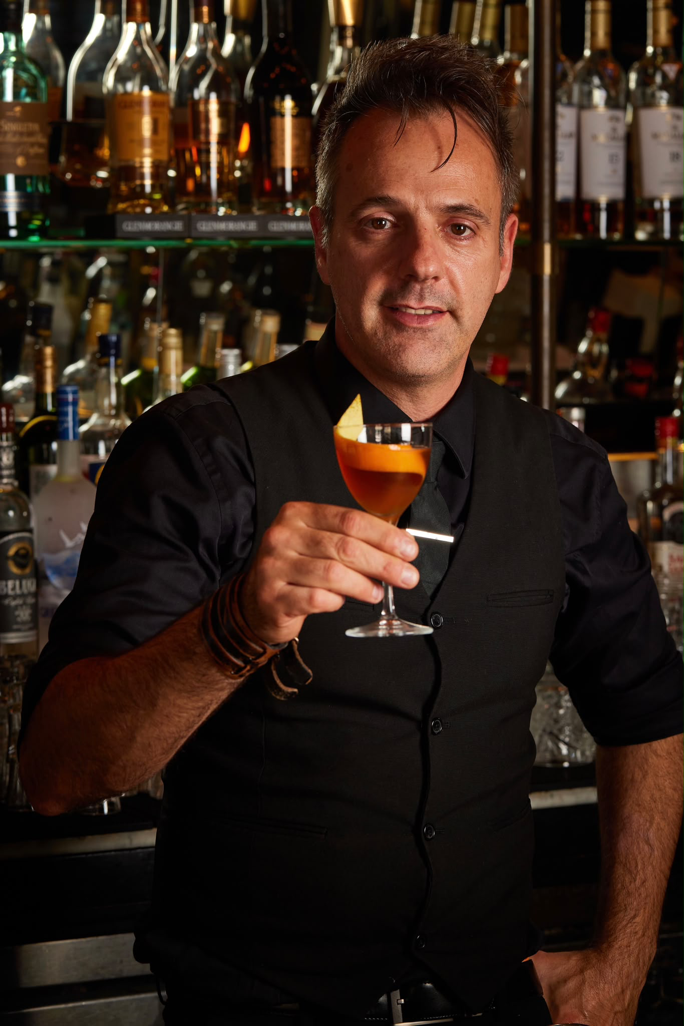Amir Babayoff holding a cocktail behind the bar at Maison Madison