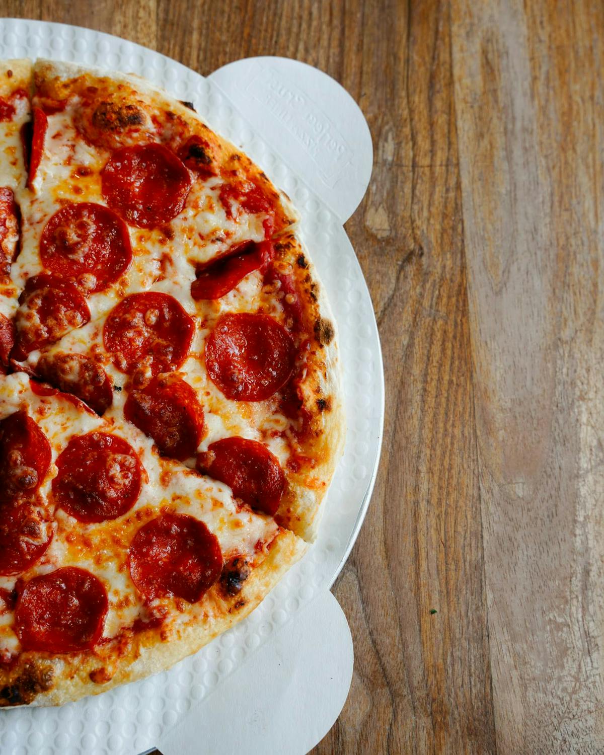 a pepperoni pizza sitting on top of a wooden table