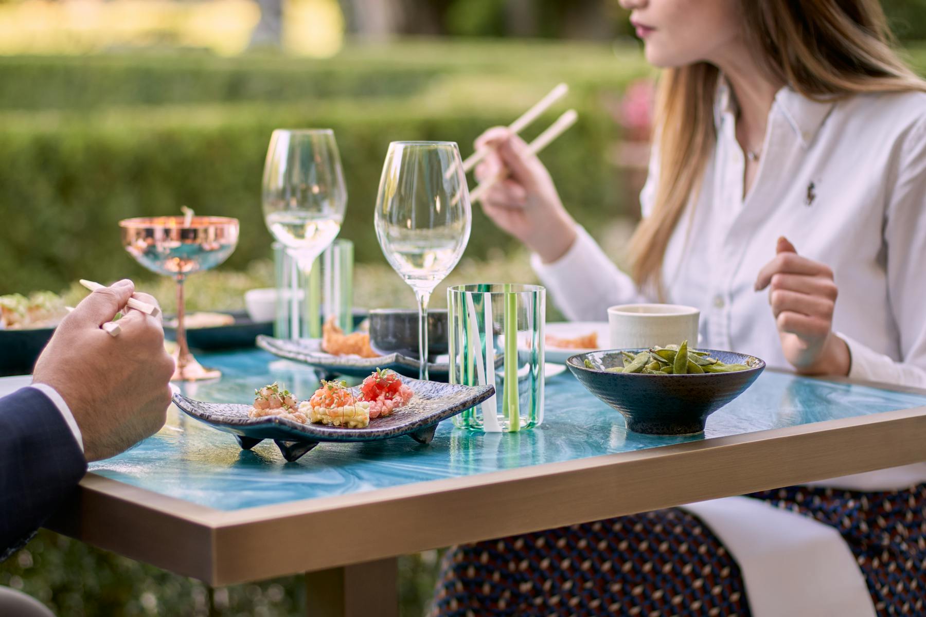 a woman sitting at a table with wine glasses