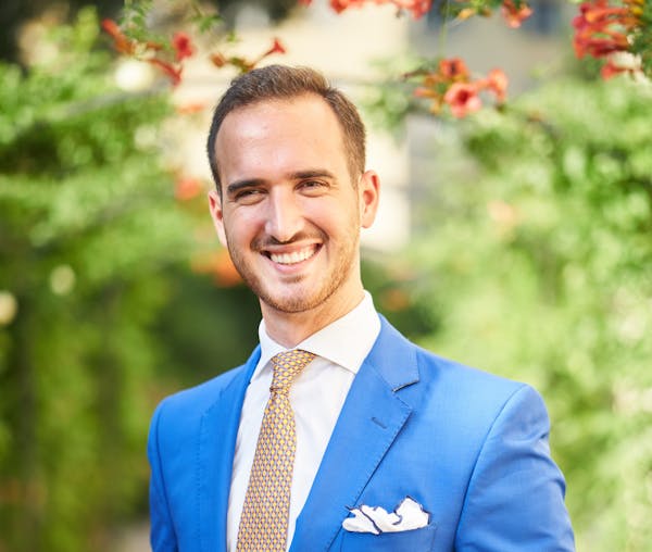 a man wearing a suit and tie smiling at the camera