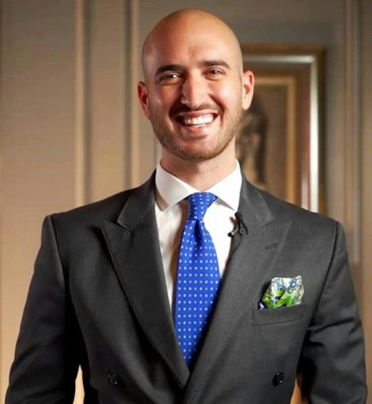a man wearing a suit and tie smiling at the camera