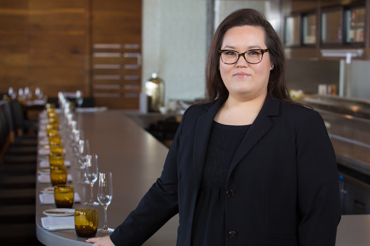 a woman wearing glasses and smiling at the camera