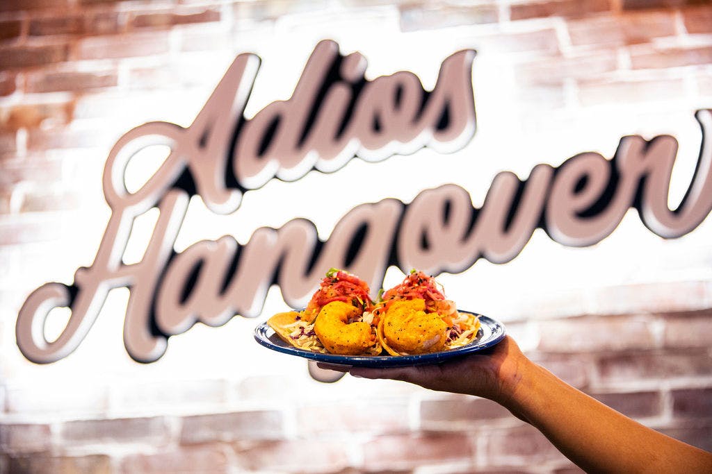 a person holding food in front of a sign