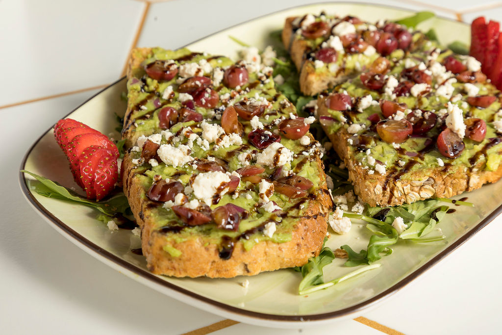 another photo of two avocados and toast with toppings a drizzle of a sauce