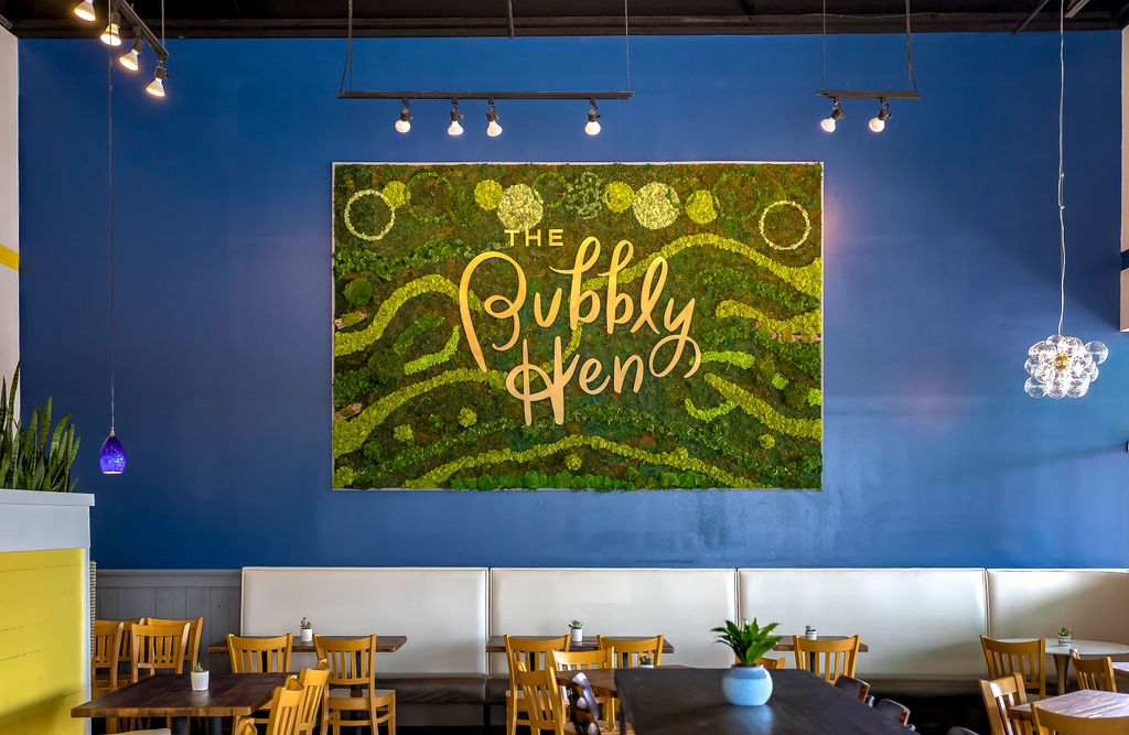 a photo the interior of Bubbly Hen with the logo on a blue wall