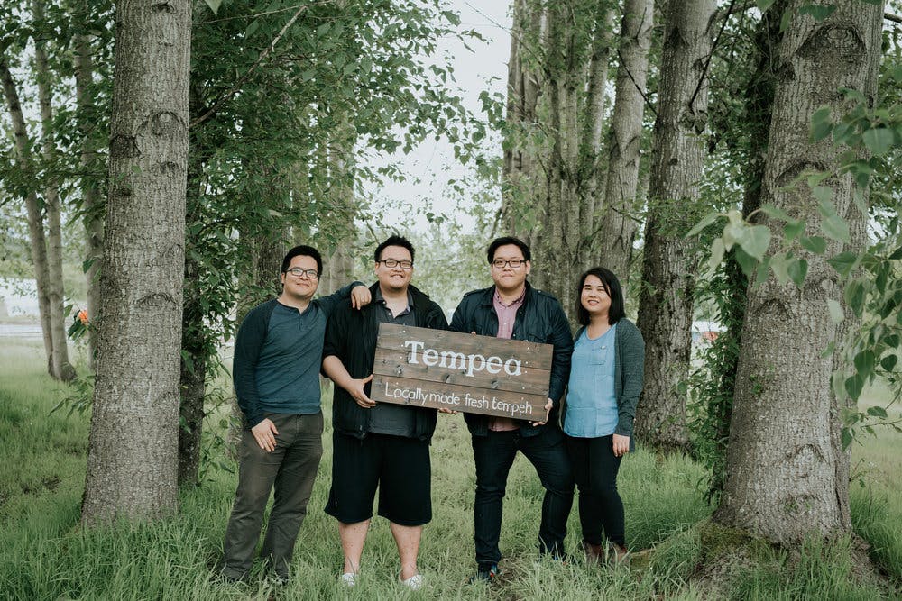 4 people holding a wooden sign that says tempea