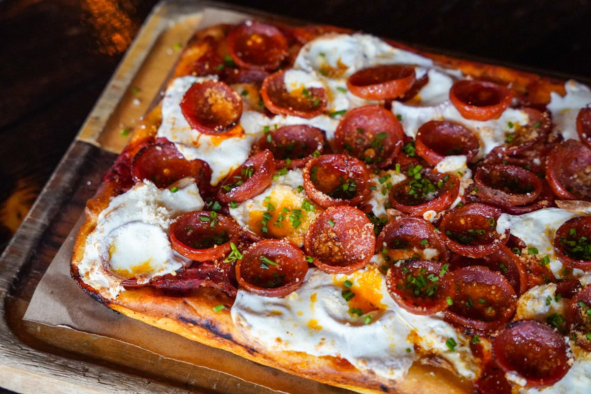 a pizza sitting on top of a wooden cutting board