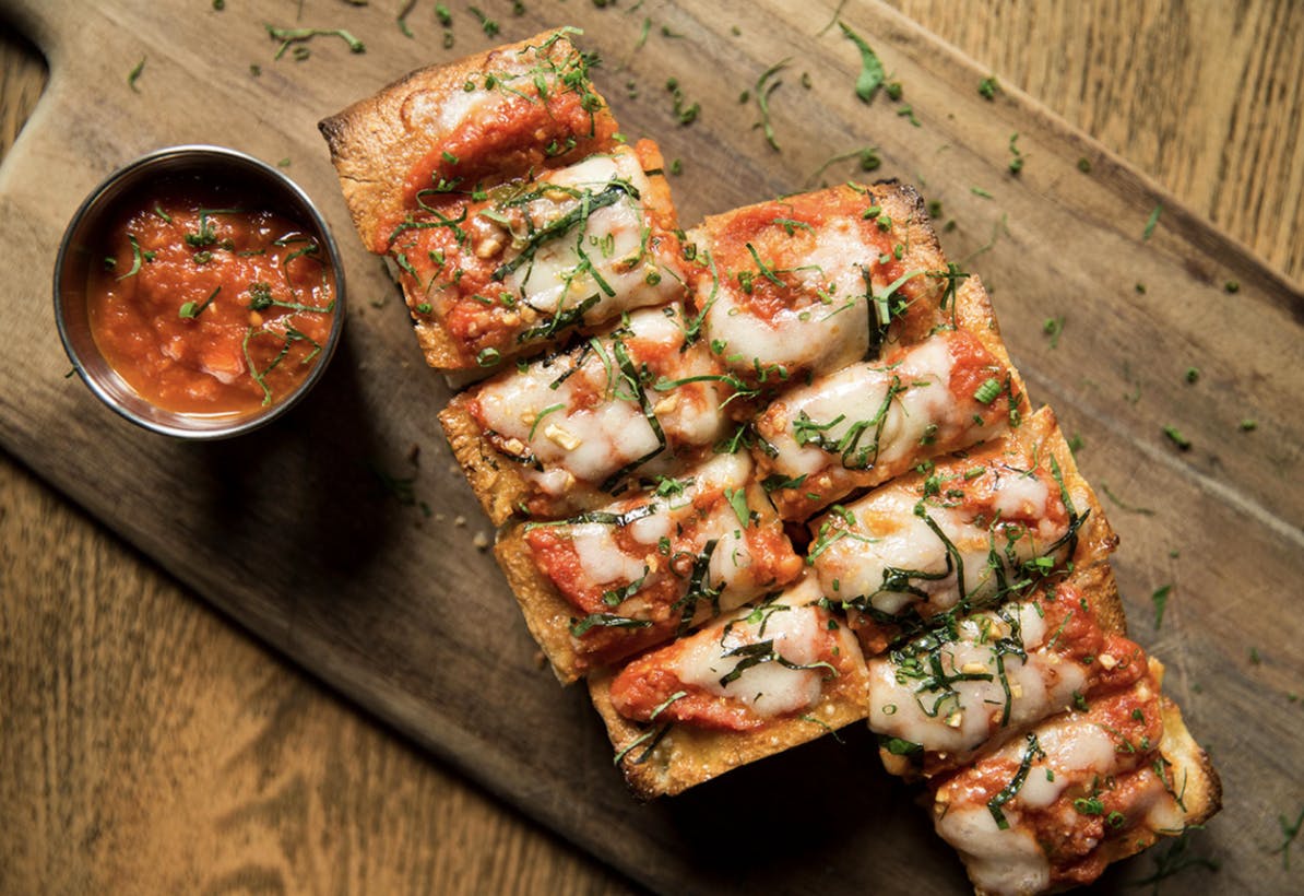 a pizza sitting on top of a wooden cutting board