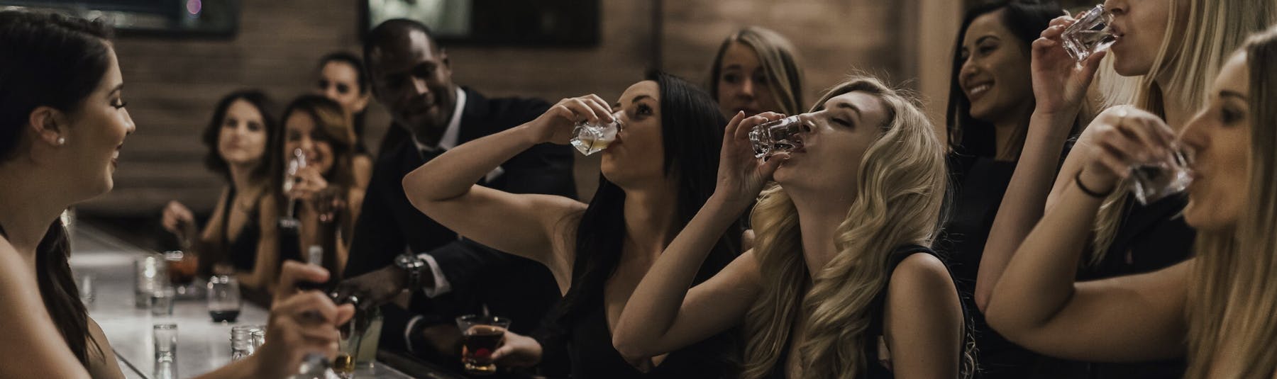 women at bar doing shots