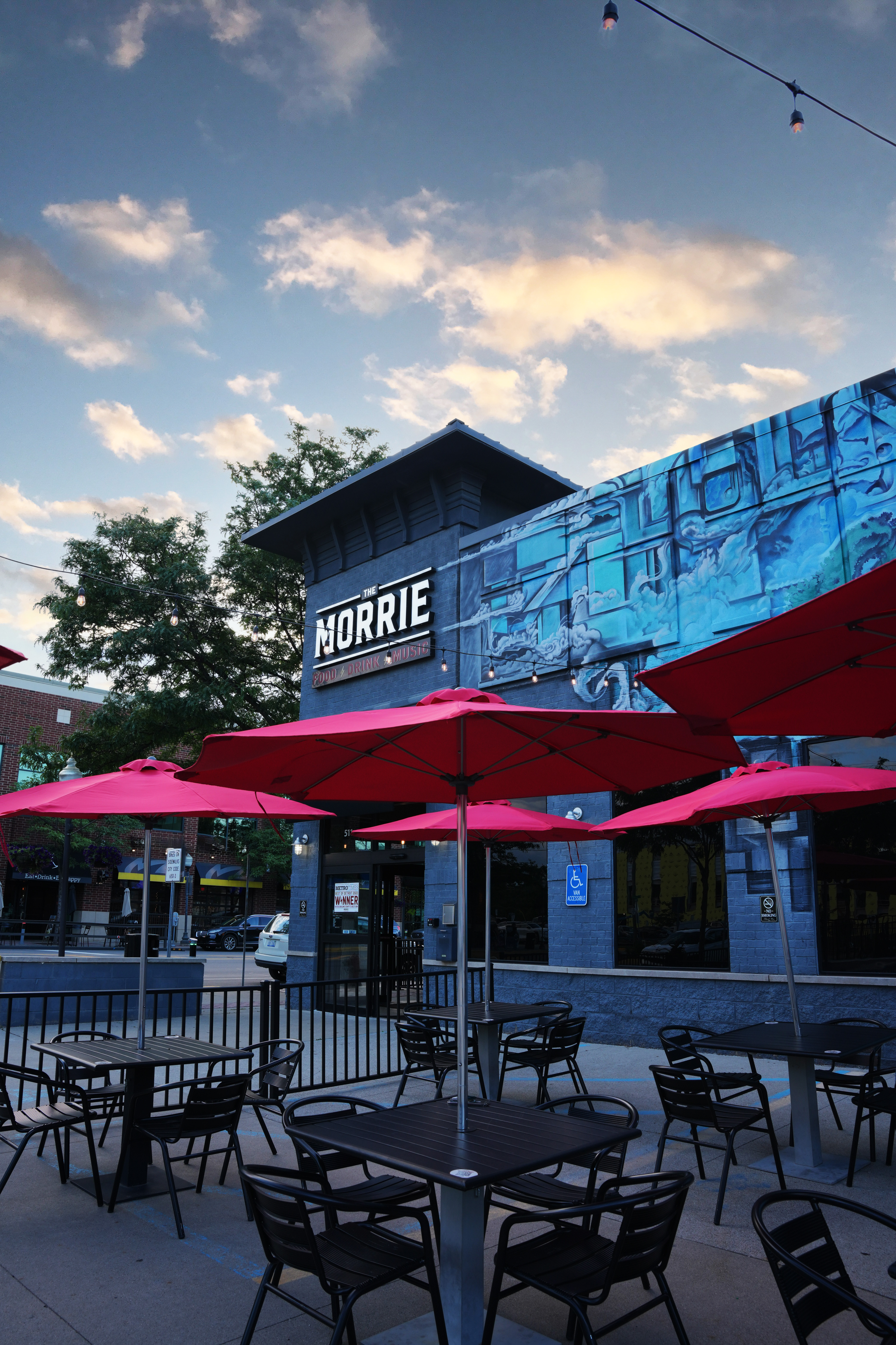 a group of people sitting at a table with a blue umbrella