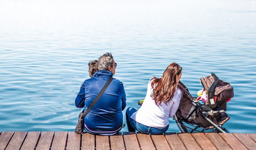 a woman sitting on a bench next to a body of water