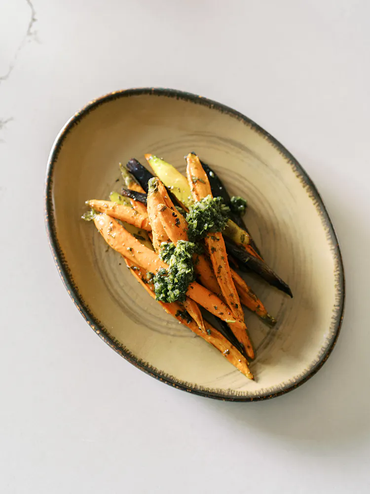a plate of carrots with green sauce