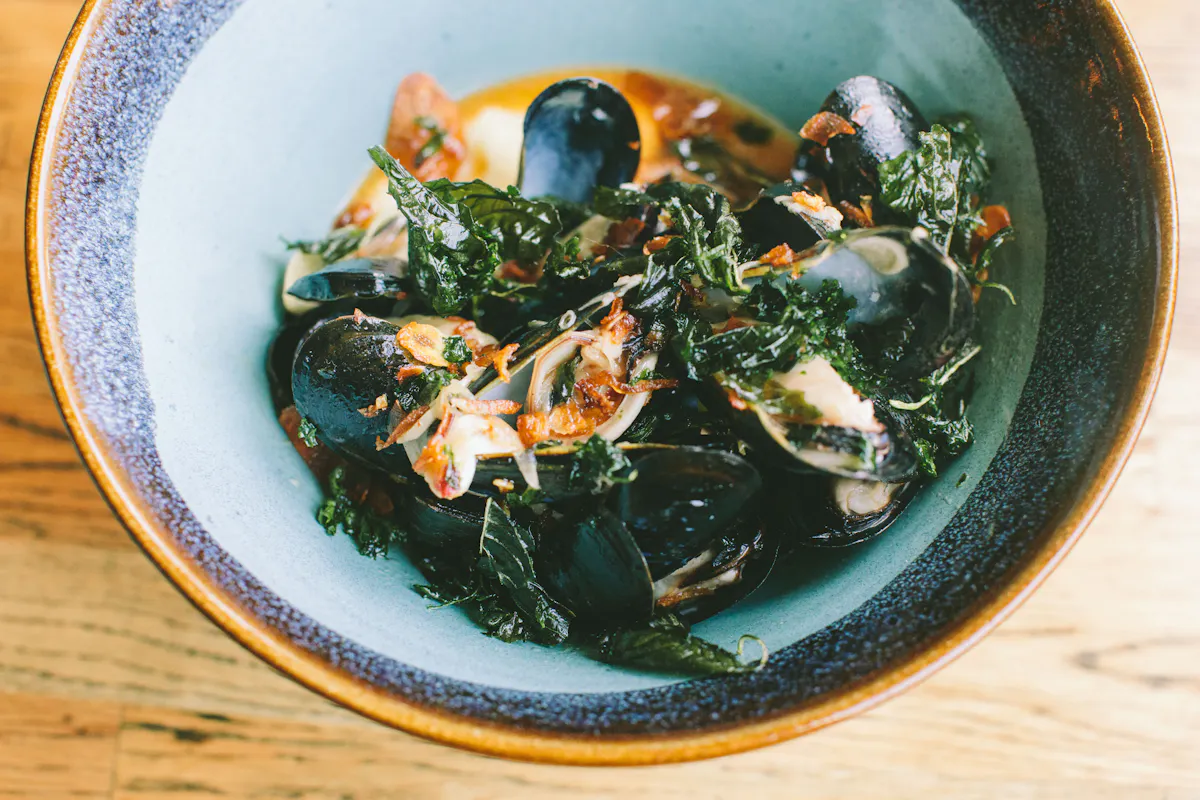 Mussels and greens served in a blue bowl