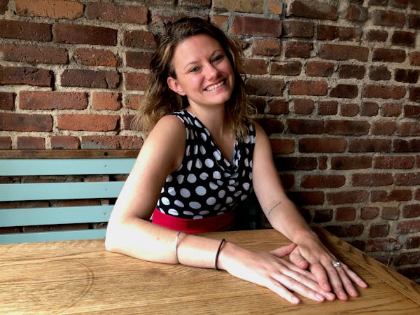 a woman sitting on a bench in front of a brick wall