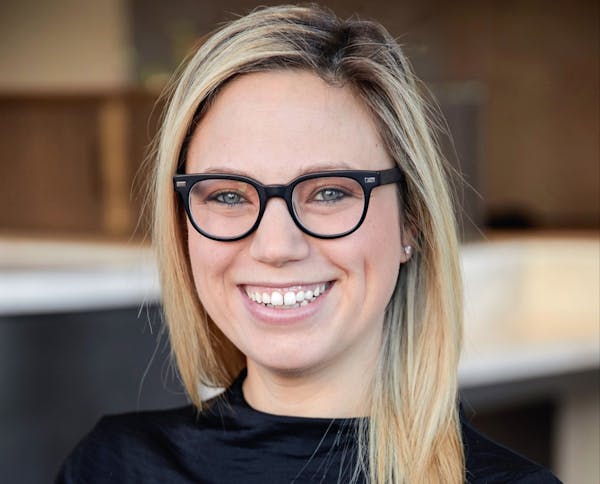 Gina-Marie Ciccotelli wearing a black shirt and glasses and smiling at the camera