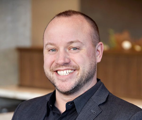 a man wearing a suit and tie smiling at the camera