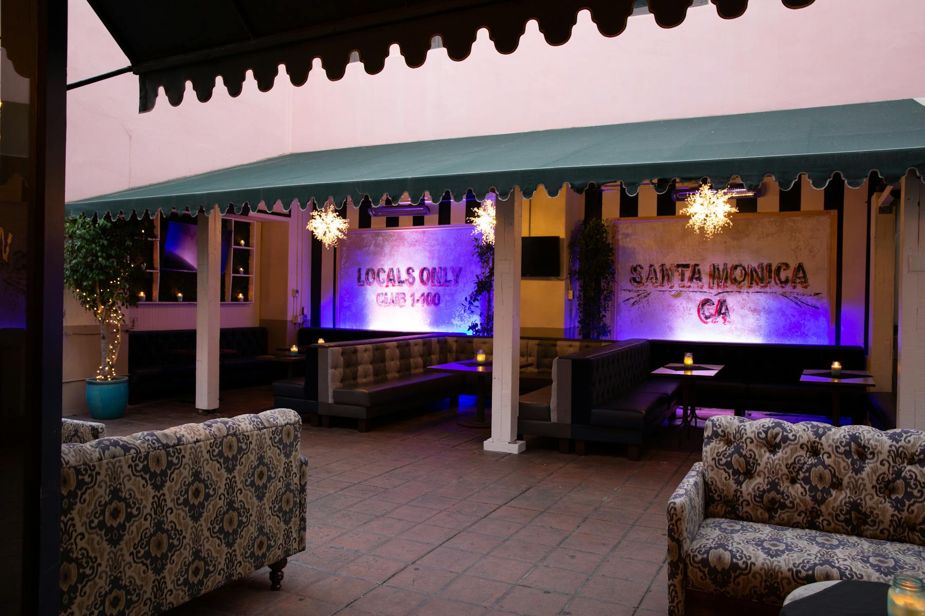 a large room filled with sitting booths and litten up with a purple light