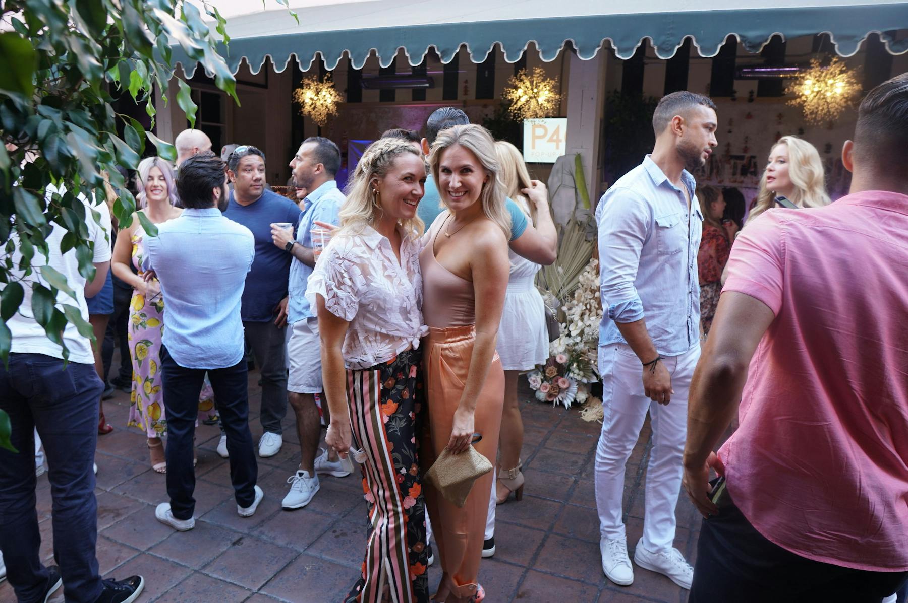 a two women standing in front of a crowd posing for the camera