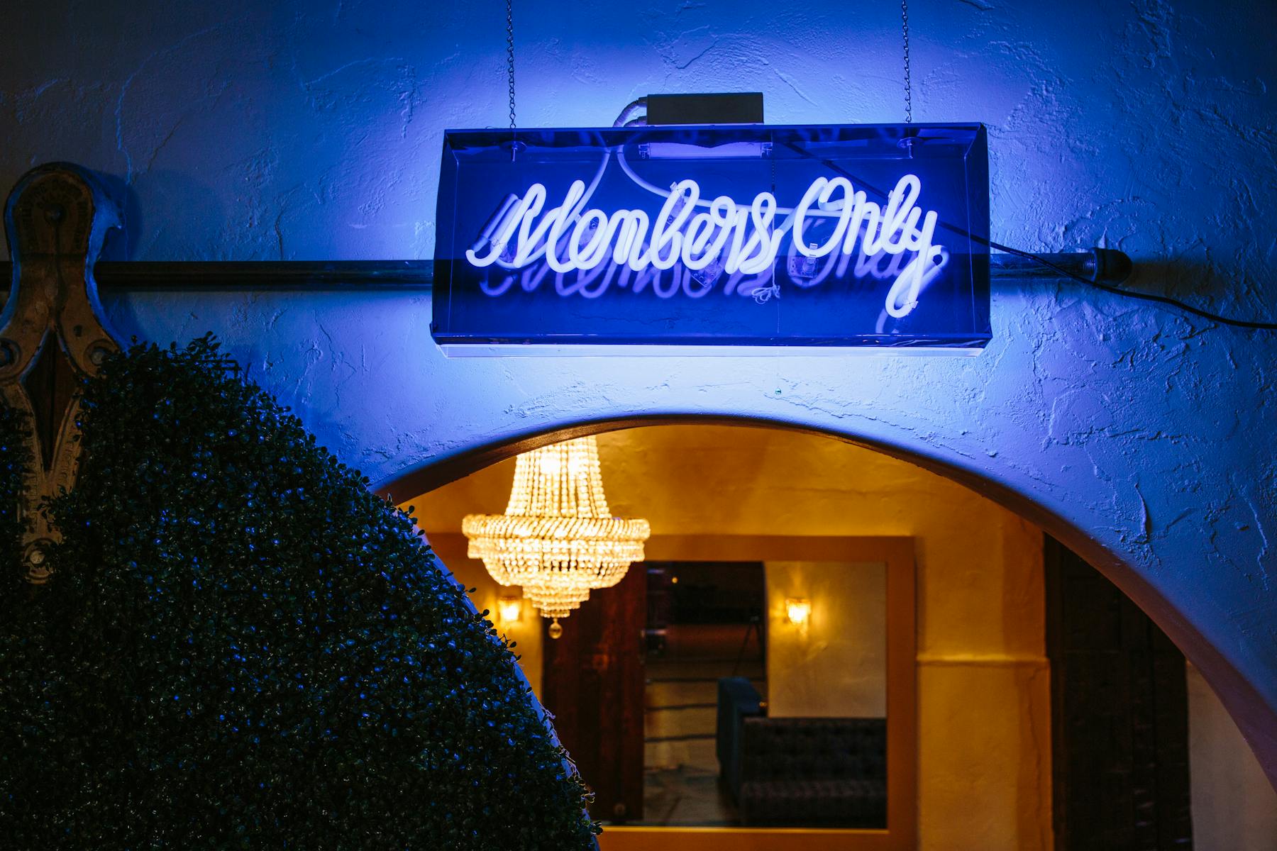 a blue neon sign above a bar entrance