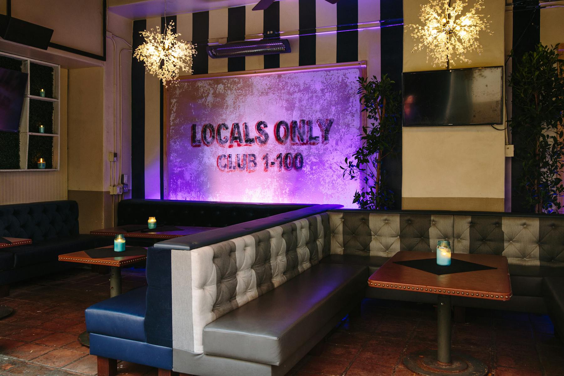 several sitting booths set beside each other in a large room litten up with purple light