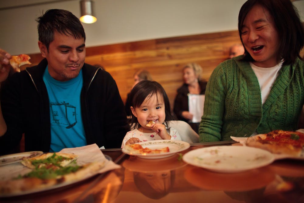 a group of people sitting at a table eating pizza