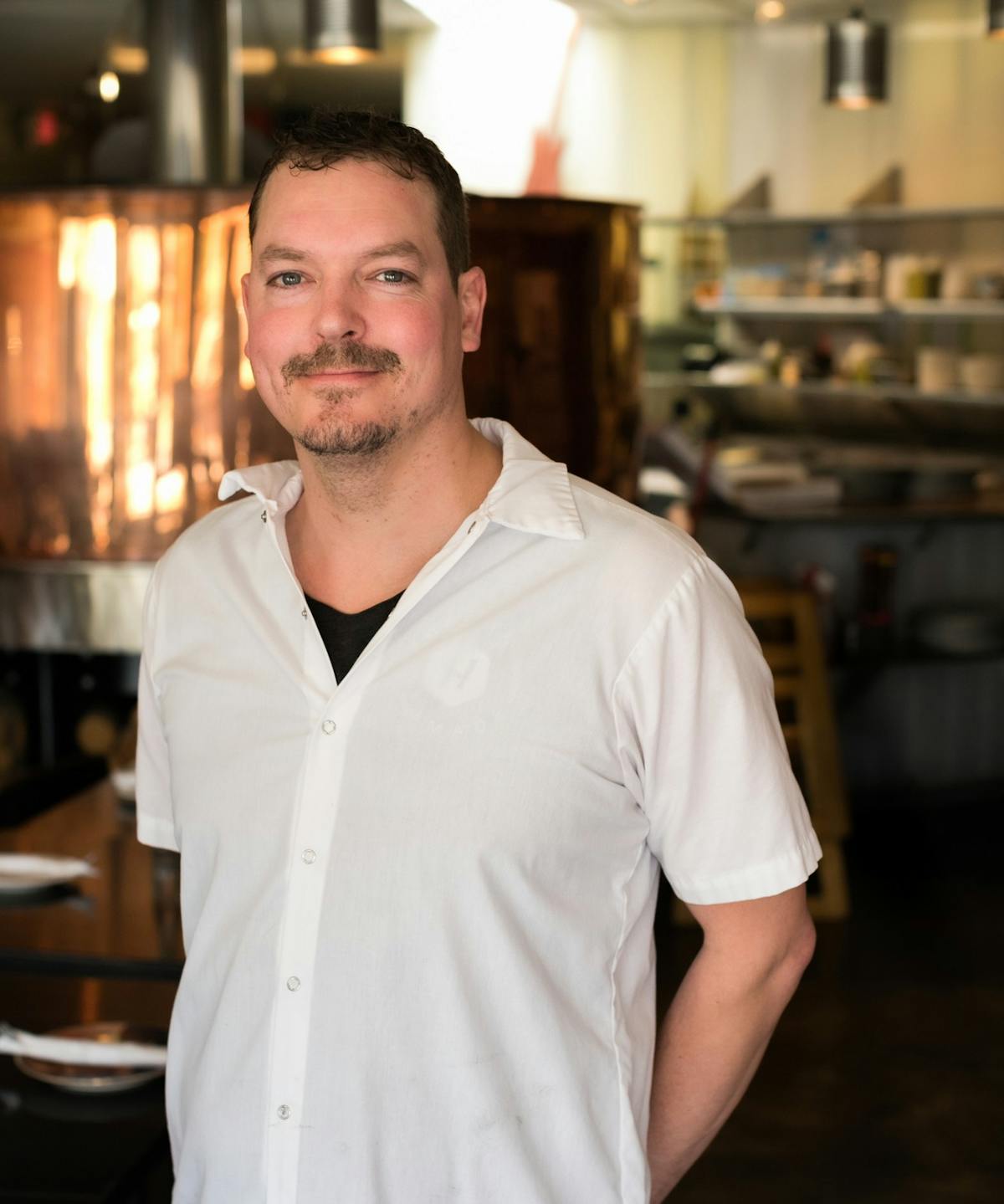Tony standing in from of the copper pizza oven