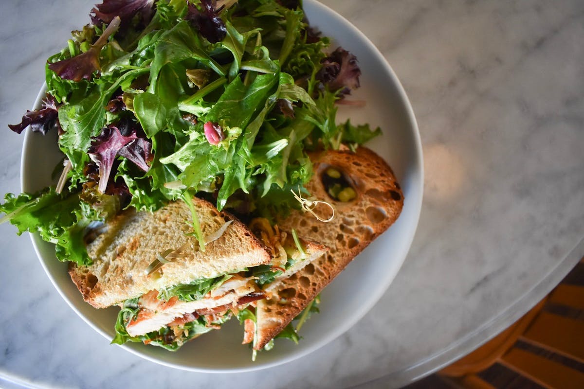 a white plate topped with a sandwich and a salad