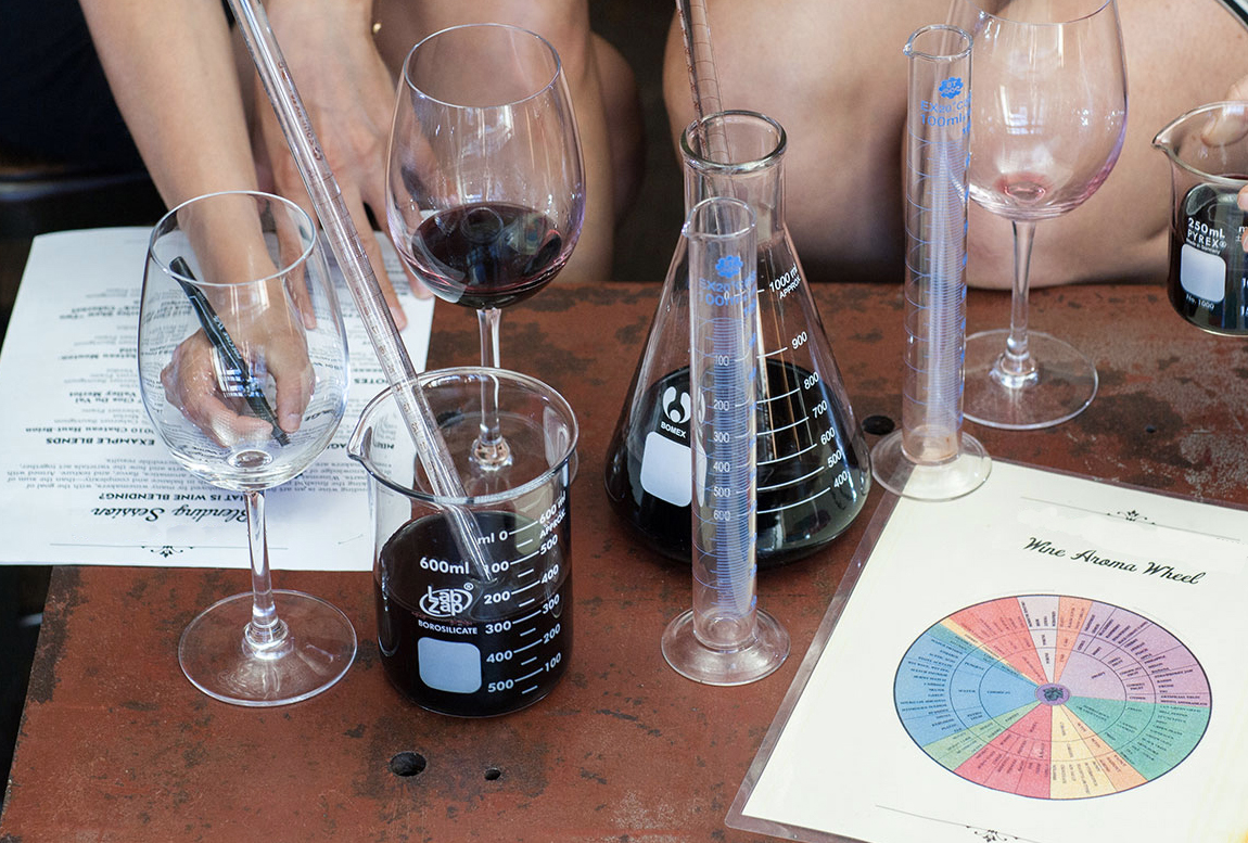 Two people blending wine with beakers and graduated cylinders