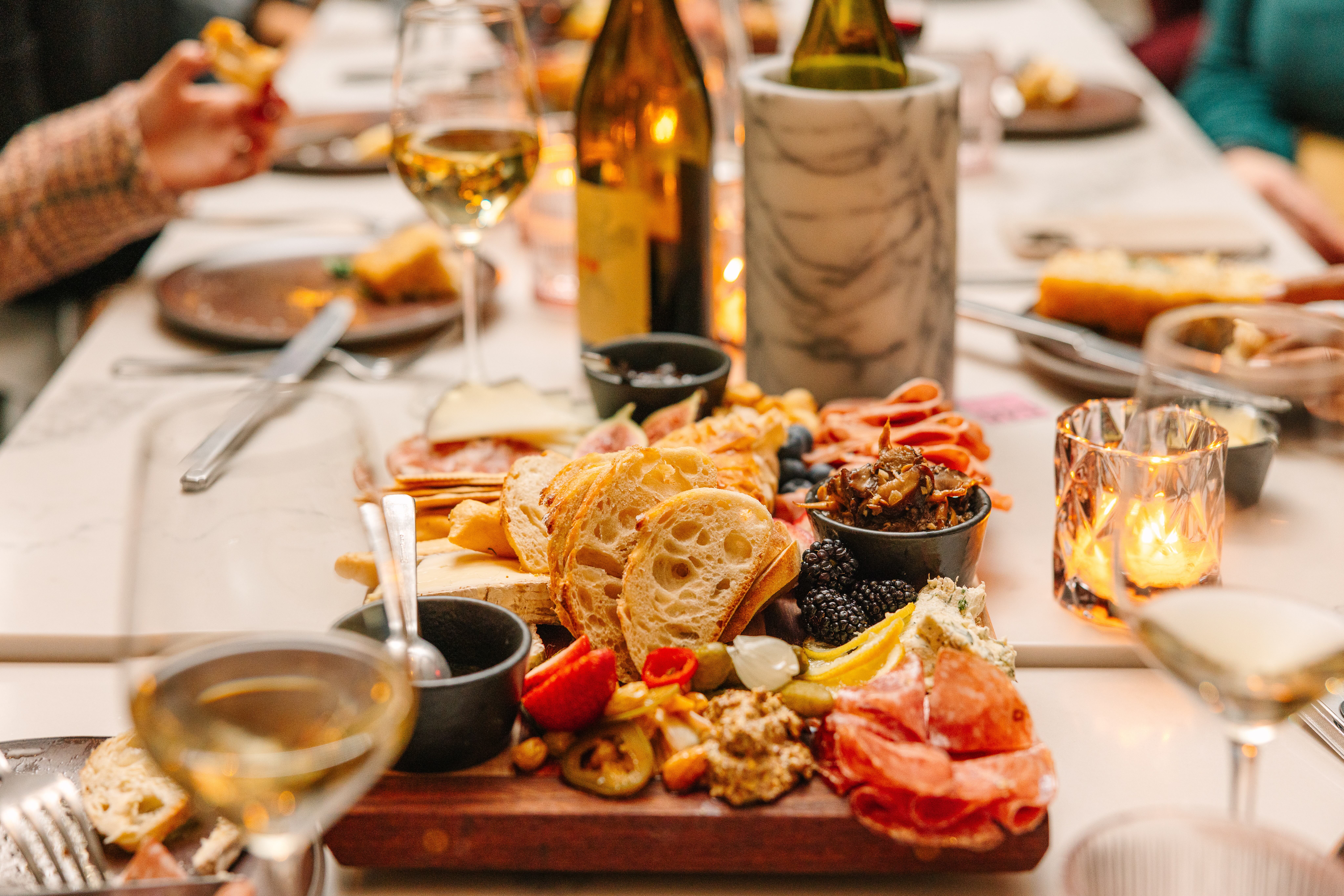 a close up of a cheese and charcuterie plate surrounded by wine