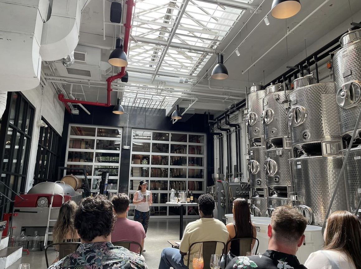a group of people watch a wine educator as she teaches about winemaking in brooklyn