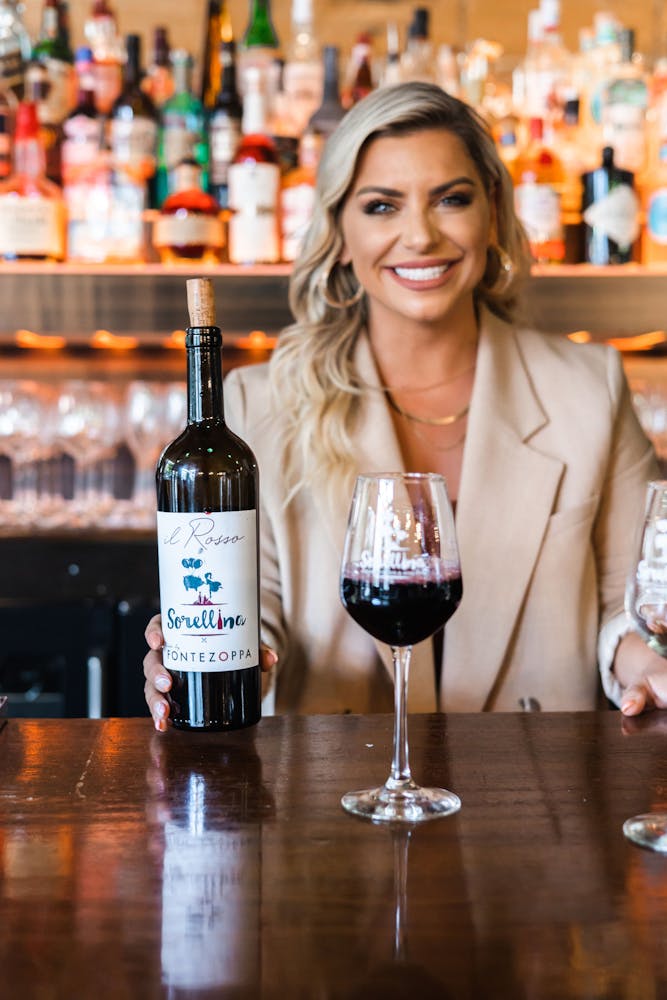 a woman sitting at a table with wine glasses