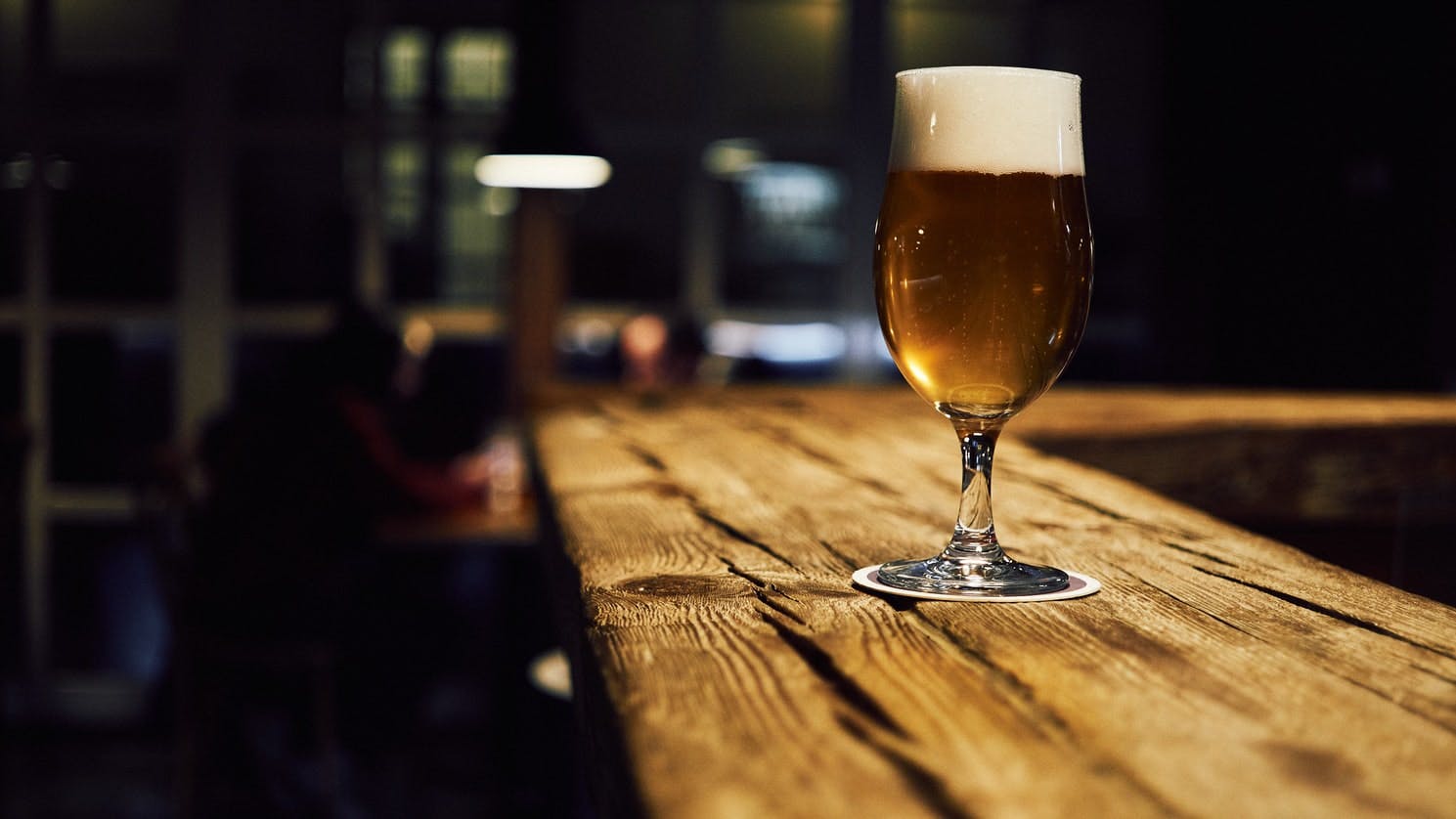 a glass filled with beer on a wooden table