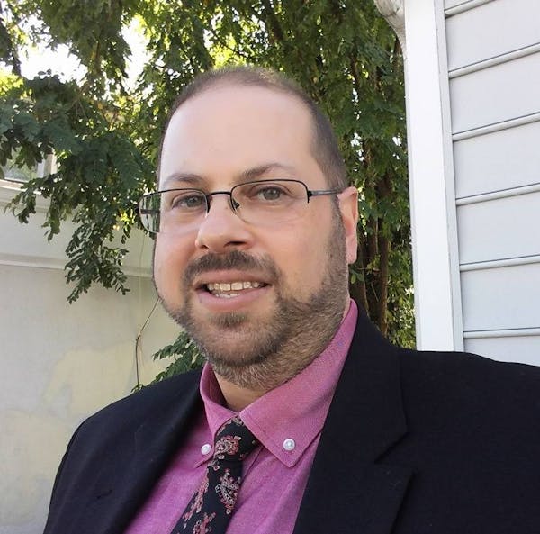 a man wearing a suit and tie smiling at the camera