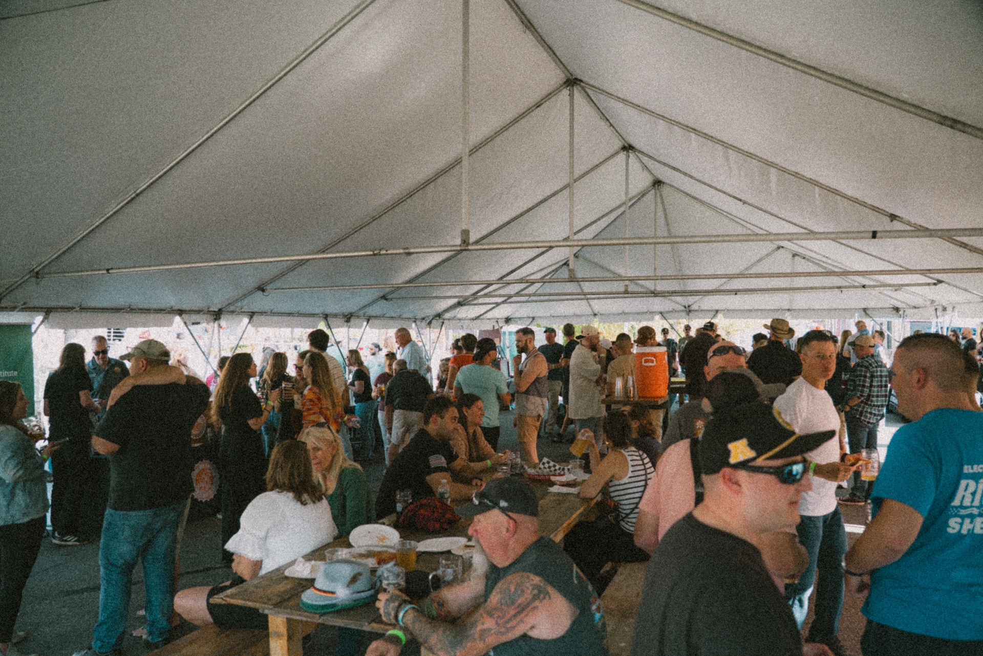 a group of people sitting at tables under a tent