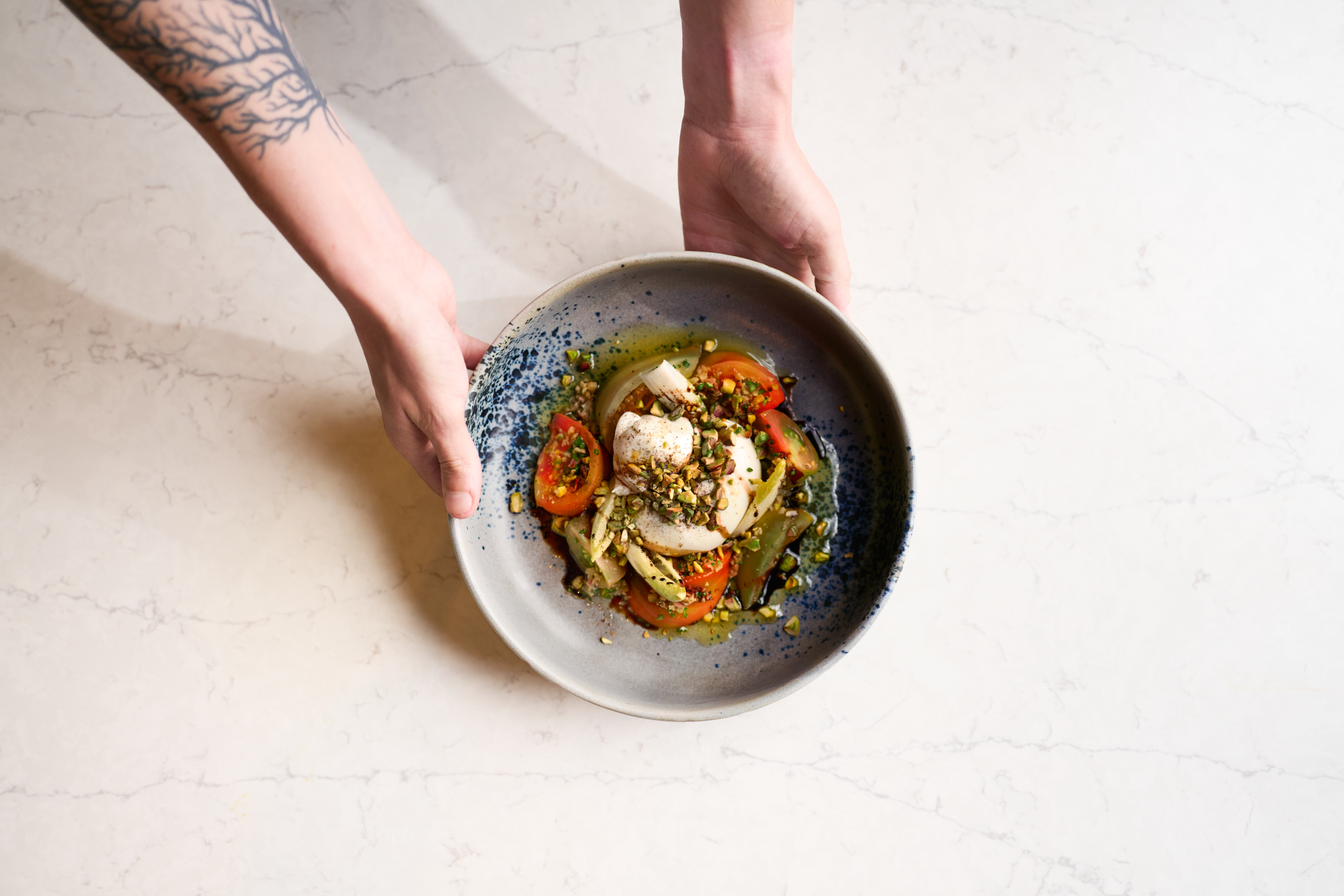 Plated burrata with tomatoes, seafood, and vegetables presented from Palmerio Restaurant’s dinner menu