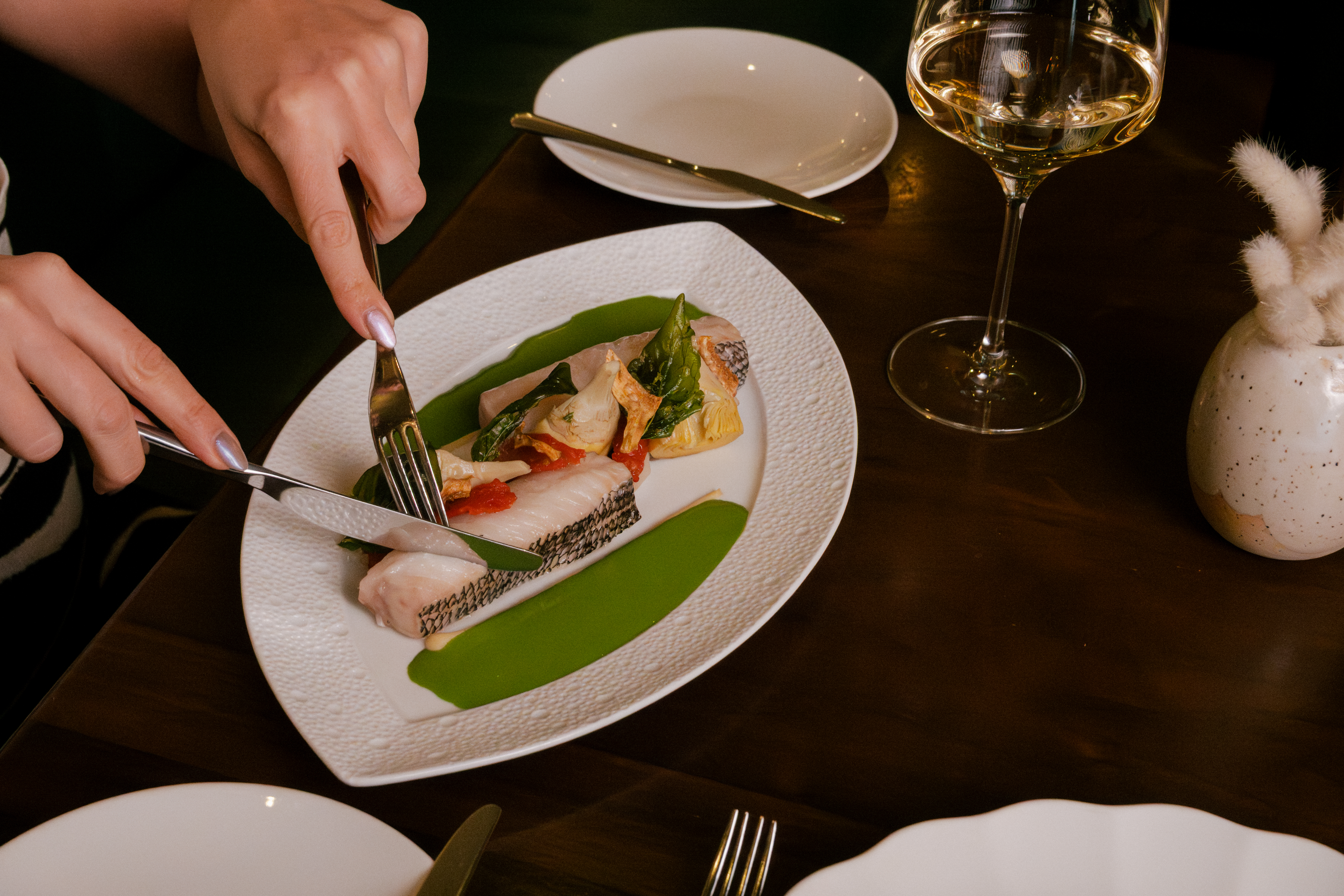 a person cutting a fish on a plate