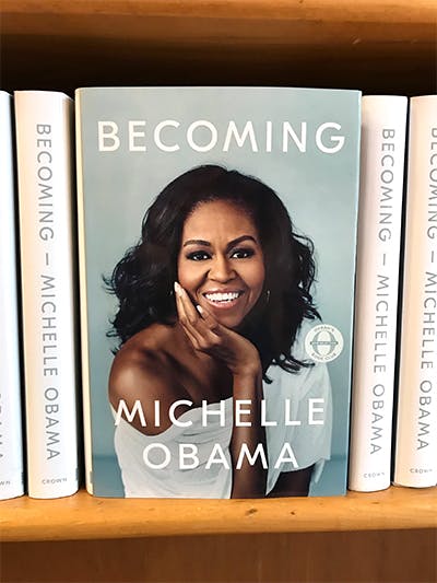 Michelle Obama sitting next to a book shelf