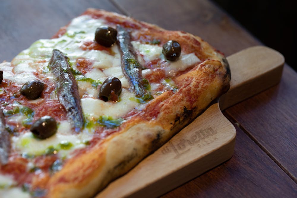 a slice of pizza sitting on top of a wooden cutting board