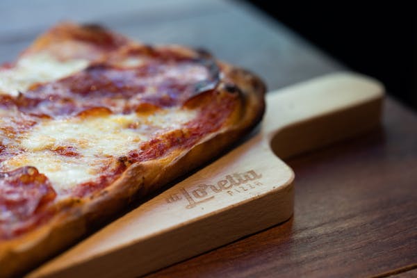 a slice of pizza sitting on top of a wooden cutting board